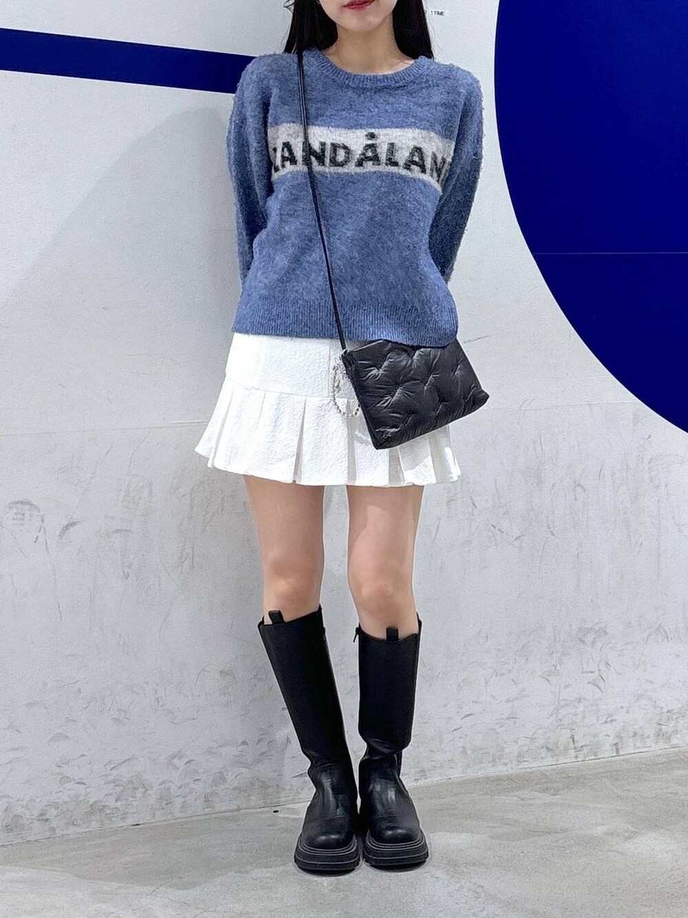 ホワイト系のスカート、ブラック系のブーツ、ブラック系のショルダーバッグを着用したレディースの秋コーディネートの2枚目の写真