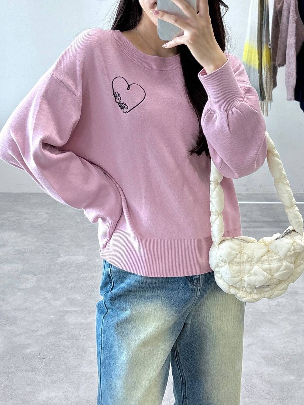 ホワイト系のショルダーバッグ、ピンク系のニット/セーター、ブルー系のデニムパンツを着用したレディースの秋コーディネートの5枚目の写真