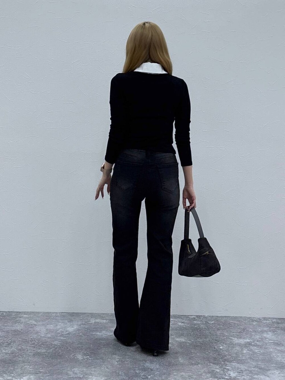 ブラック系のローファー、グレー系のハンドバッグ、ブラック系のデニムパンツを着用したレディースの秋コーディネートの5枚目の写真