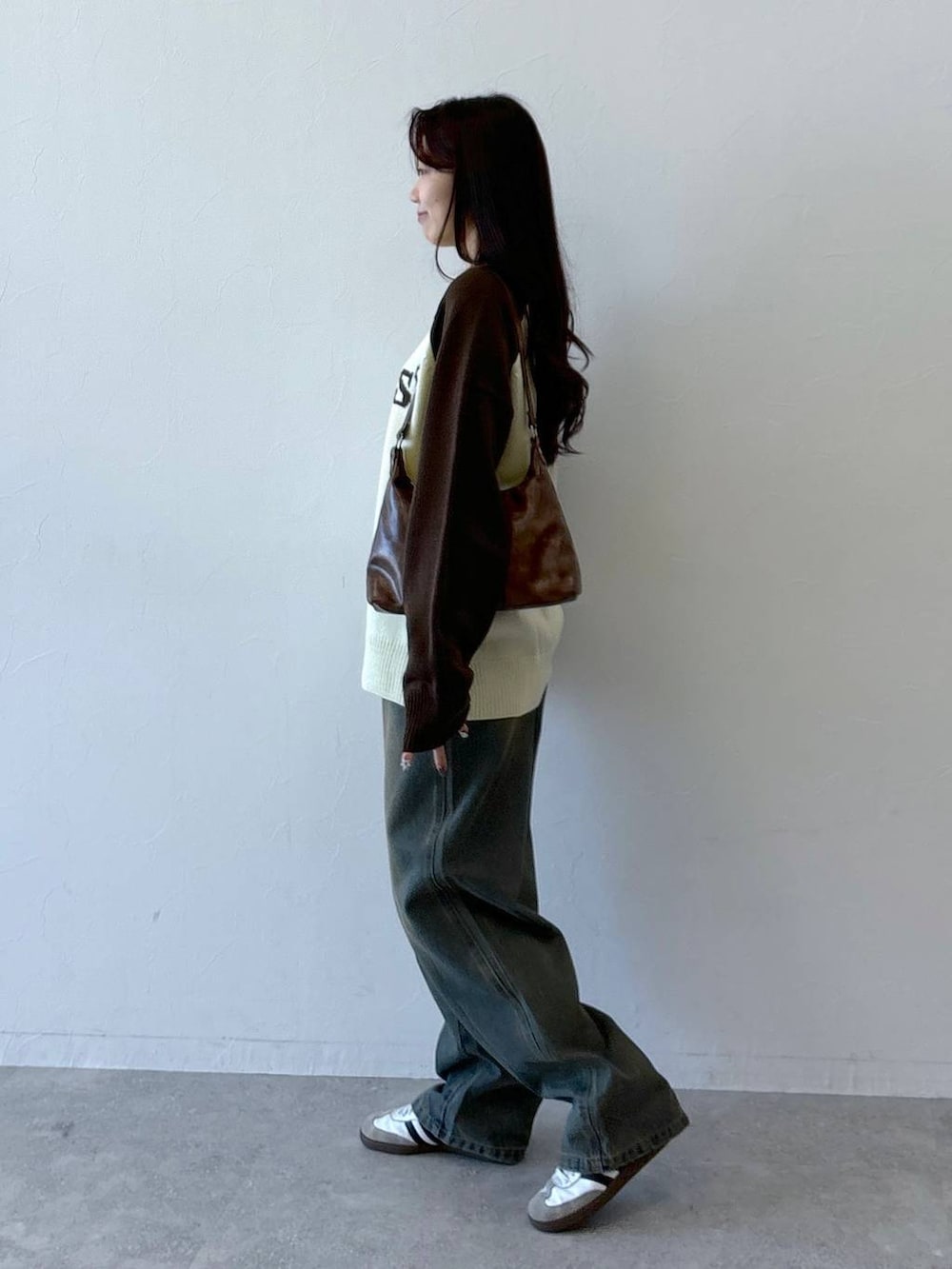 ブラウン系のニット/セーター、ブルー系のデニムパンツ、ブラウン系のハンドバッグを着用したレディースの冬コーディネートの4枚目の写真