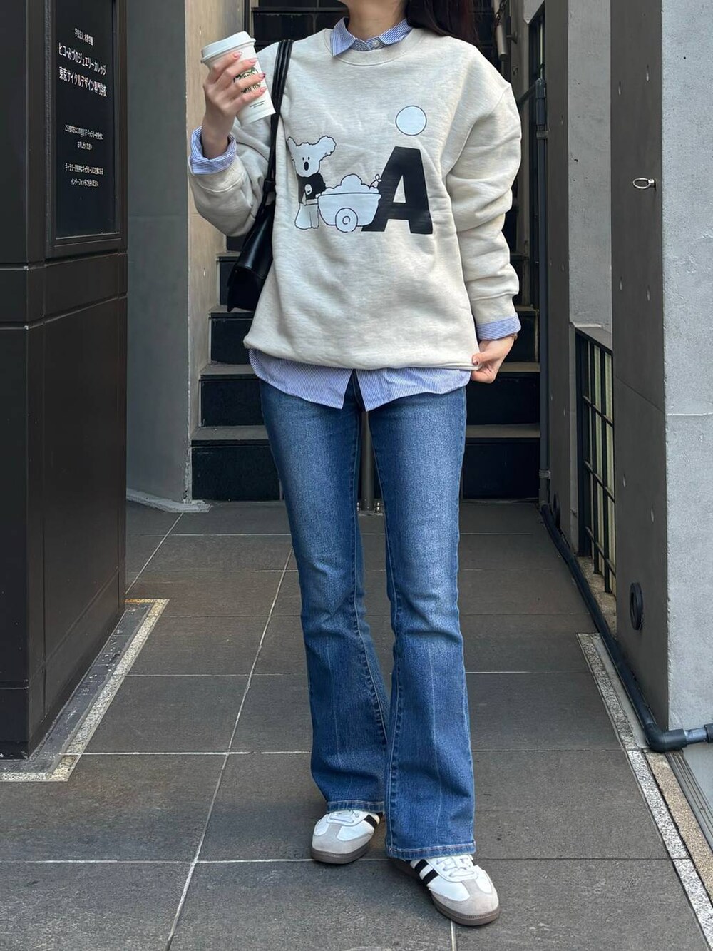 ブルー系のデニムパンツ、ブラック系のショルダーバッグ、ベージュ系のスウェットを着用したレディースの冬コーディネートの3枚目の写真