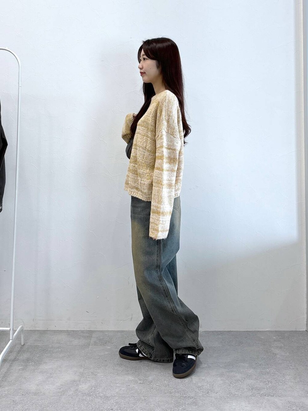 ブラック系のトートバッグ、ブルー系のデニムパンツ、ベージュ系のニット/セーターを着用したレディースの秋コーディネートの3枚目の写真