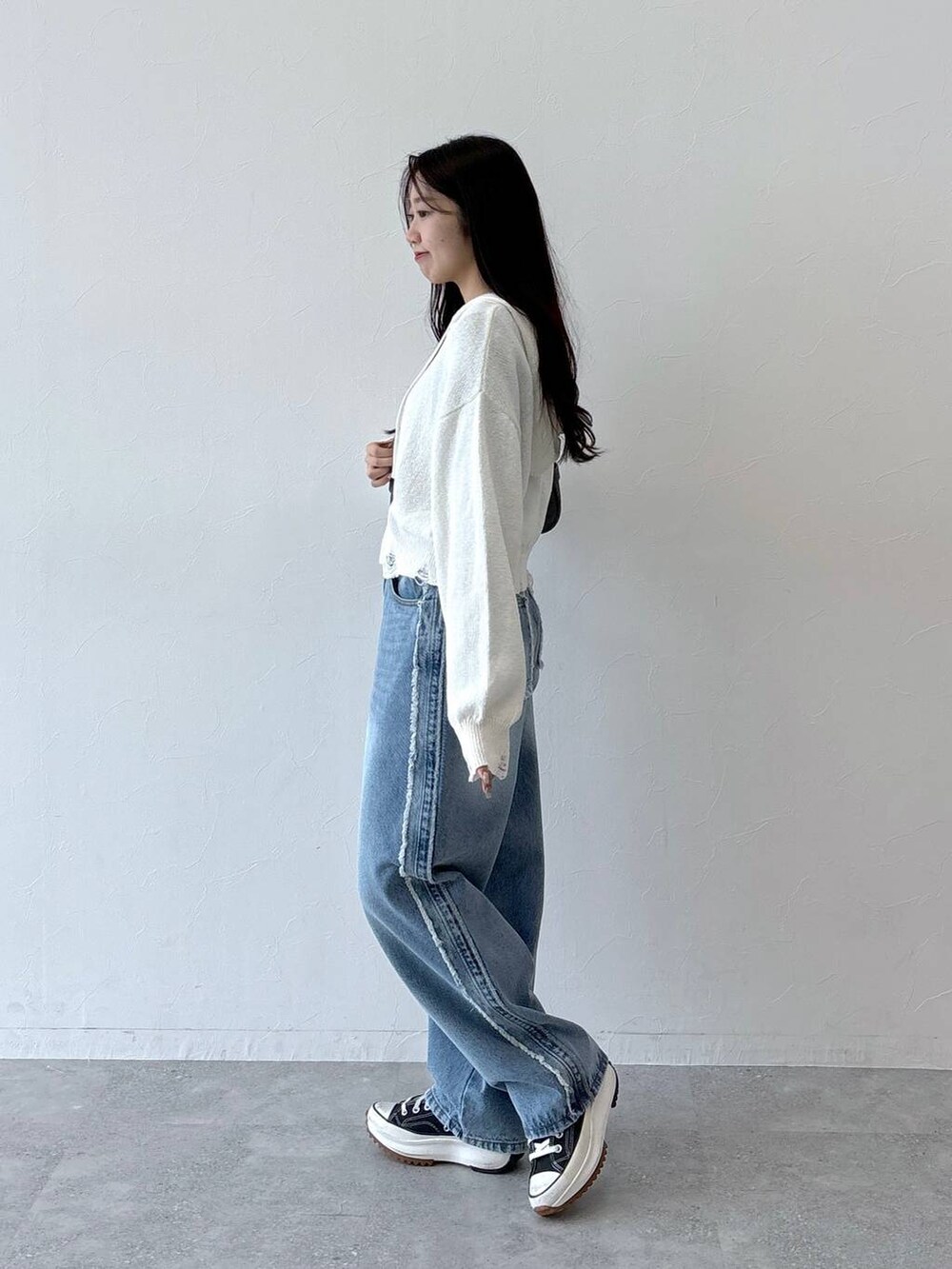 ブラック系のトートバッグ、ブラック系のTシャツ/カットソー、ブルー系のデニムパンツを着用したレディースの秋コーディネートの5枚目の写真