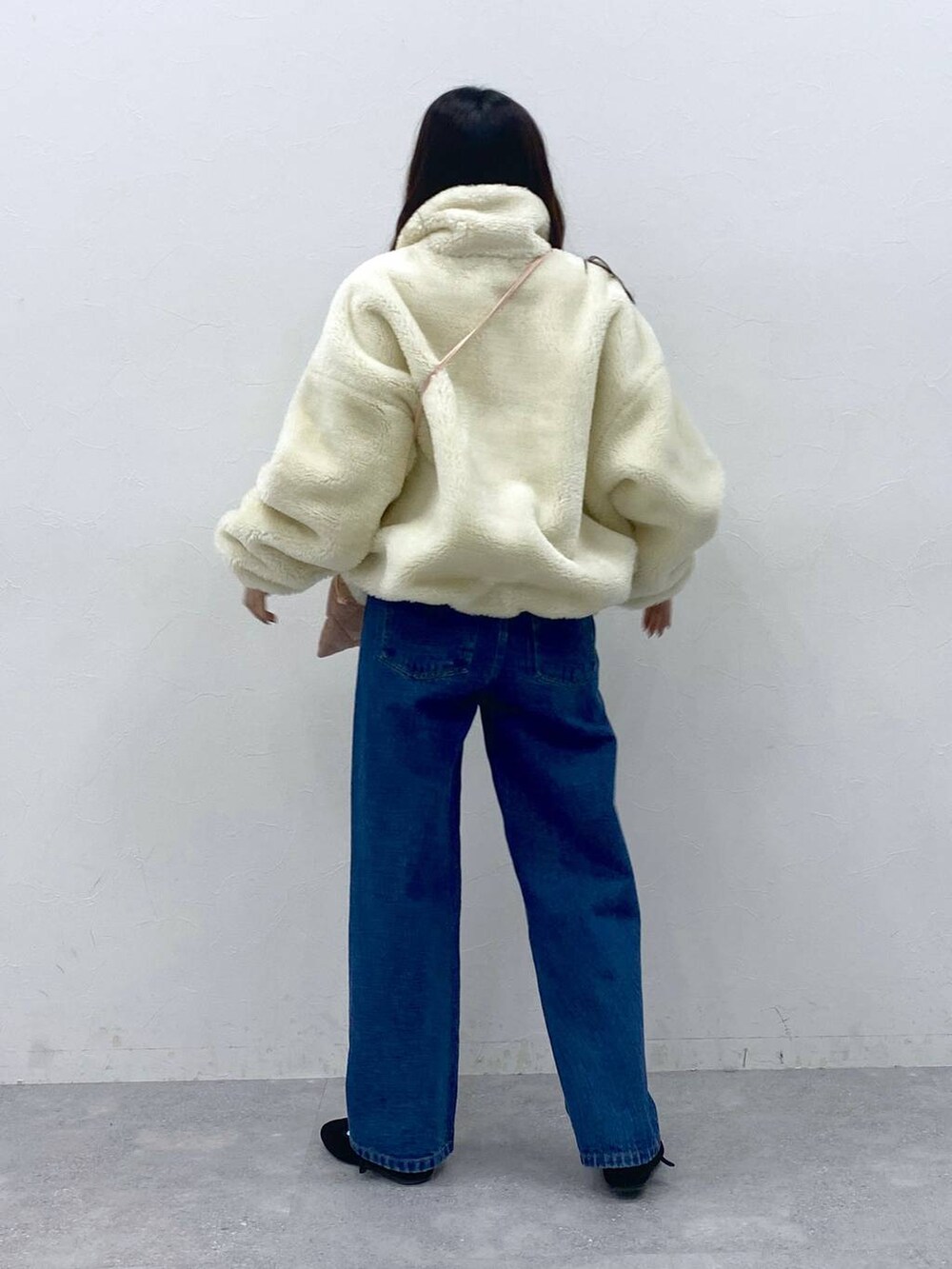 ブラック系のパンプス、ピンク系のショルダーバッグ、ブルー系のデニムパンツを着用したレディースの冬コーディネートの4枚目の写真