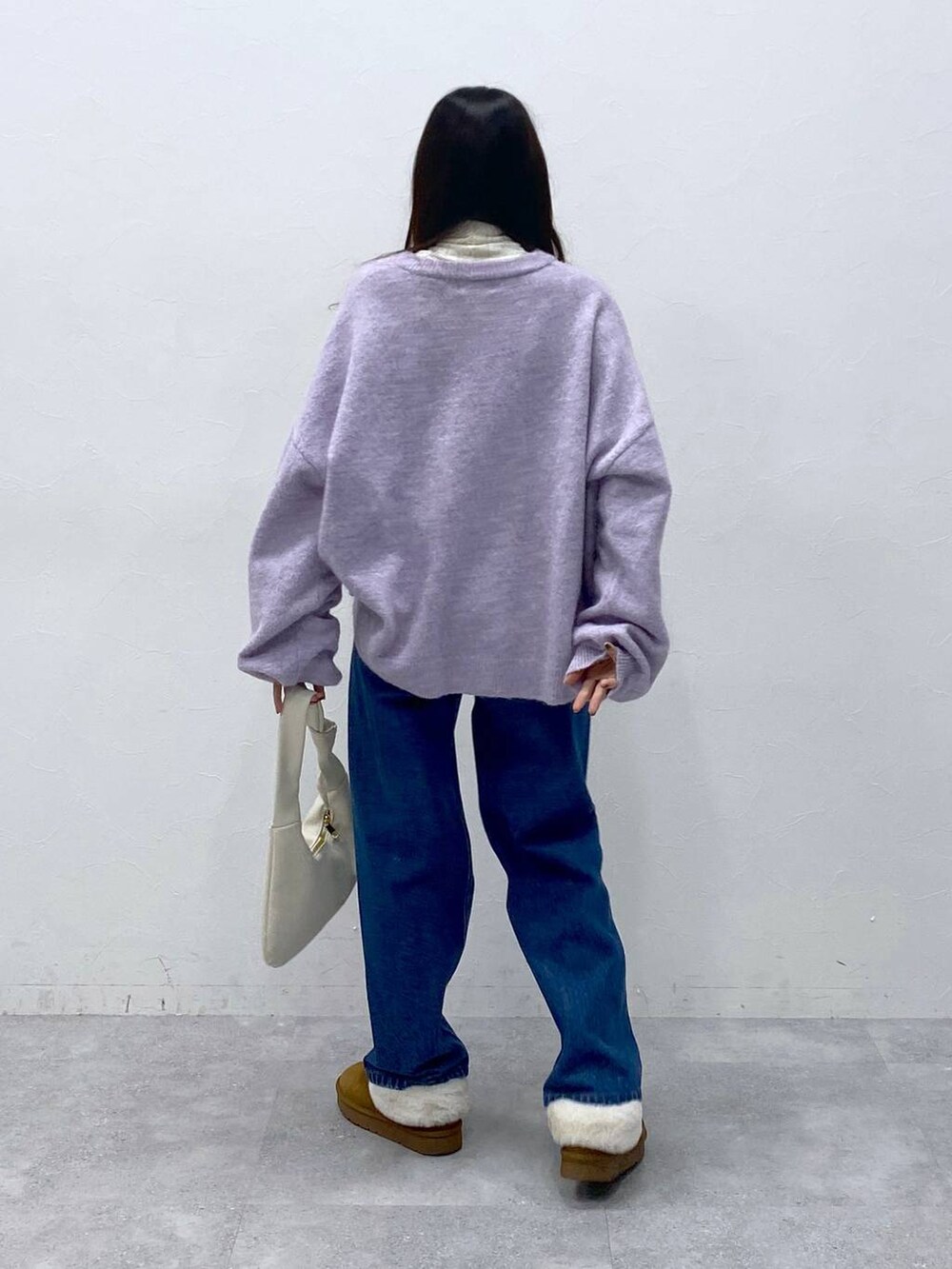 ブルー系のデニムパンツ、ベージュ系のTシャツ/カットソー、パープル系のニット/セーターを着用したレディースの冬コーディネートの4枚目の写真