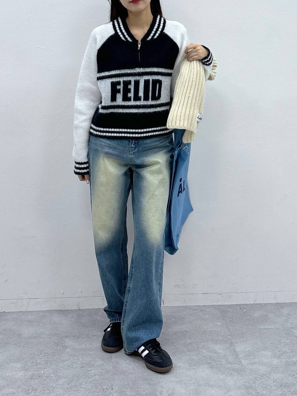 ブルー系のトートバッグ、ブルー系のデニムパンツ、ホワイト系のニット/セーターを着用したレディースの秋コーディネートの3枚目の写真