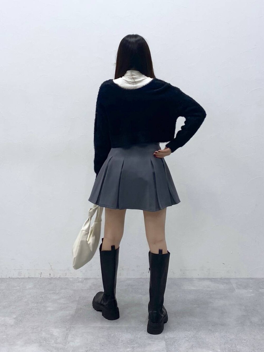 ブラック系のカーディガン/ボレロ、ベージュ系のTシャツ/カットソー、グレー系のスカートを着用したレディースの冬コーディネートの4枚目の写真