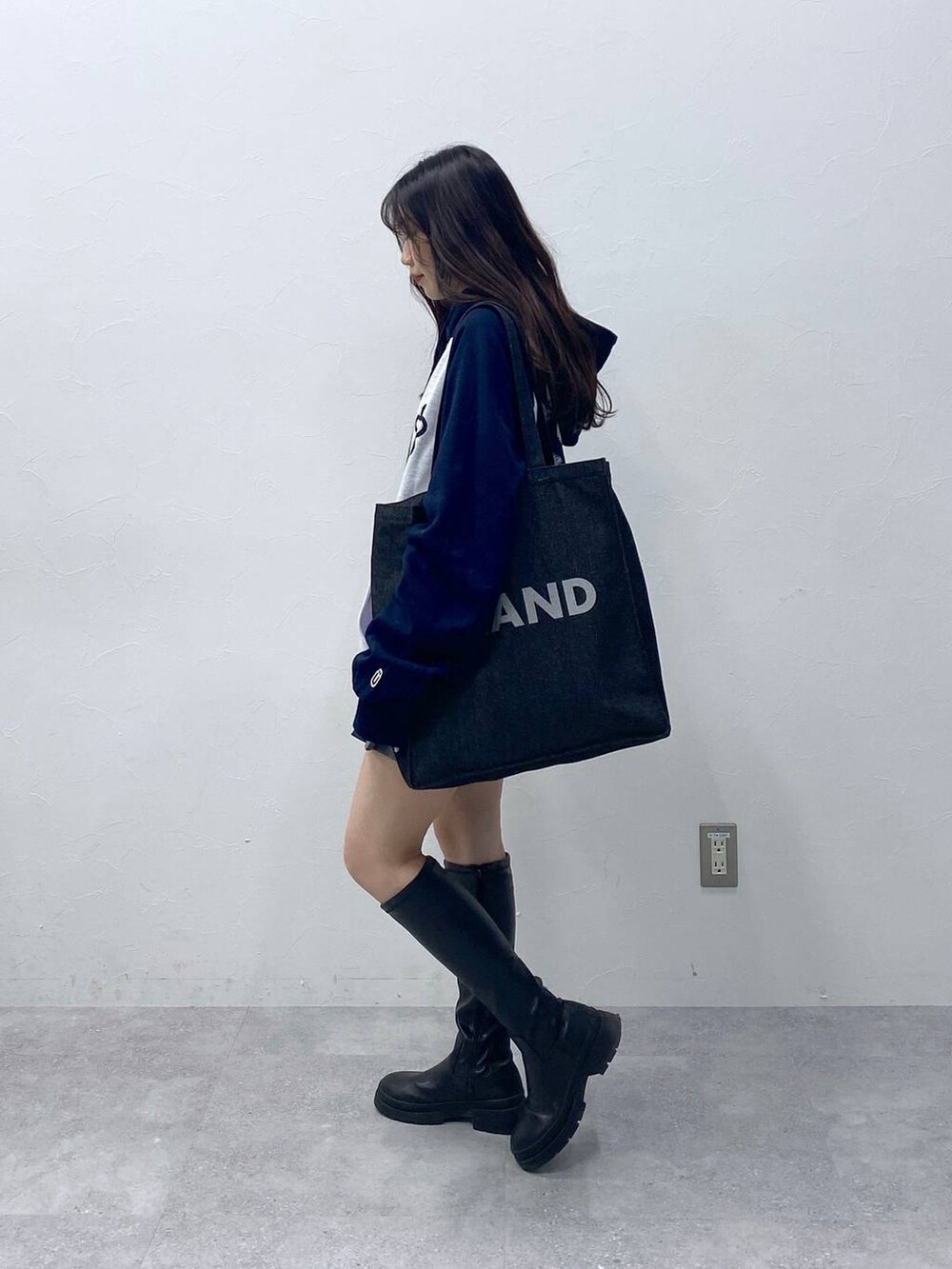 グレー系のスカート、ブルー系のトートバッグ、ブルー系のパーカーを着用したレディースの冬コーディネートの3枚目の写真