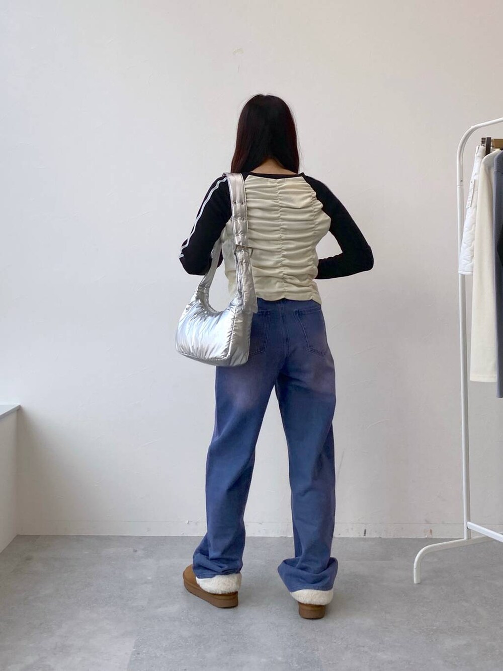 パープル系のデニムパンツ、その他のショルダーバッグ、ベージュ系のTシャツ/カットソーを着用したレディースの冬コーディネートの4枚目の写真