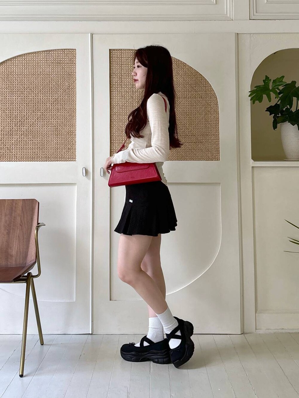 レッド系のショルダーバッグ、ベージュ系のTシャツ/カットソー、ブラック系のスカートを着用したレディースの秋コーディネートの4枚目の写真