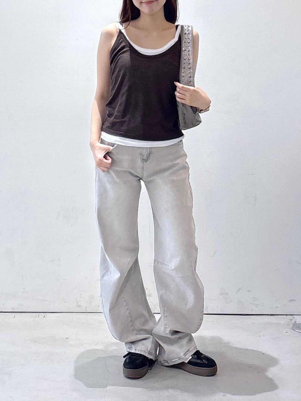 グレー系のデニムパンツ、ブラウン系のタンクトップ、グレー系のハンドバッグを着用したレディースの夏コーディネートの2枚目の写真