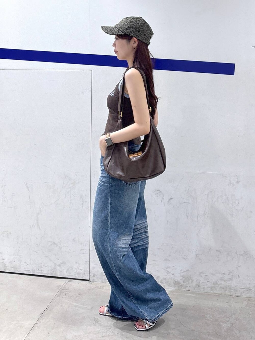シルバー系のサンダル、ブルー系のデニムパンツ、ブラウン系のトートバッグを着用したレディースの夏コーディネートの3枚目の写真