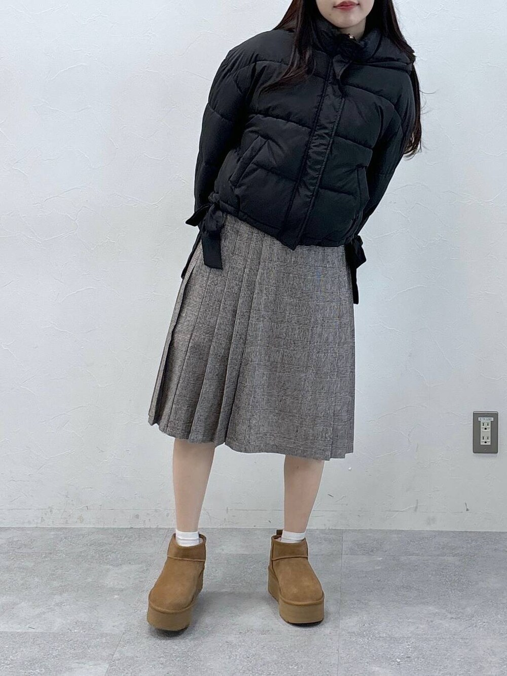 ブラック系のダウンジャケット/コート、ブラウン系のスカートを着用したレディースの秋コーディネートの2枚目の写真