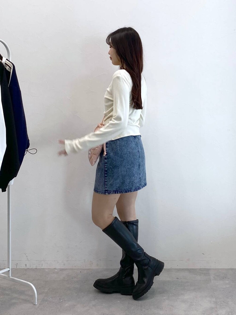 ブルー系のデニムスカート、ピンク系のショルダーバッグ、ベージュ系のTシャツ/カットソーを着用したレディースの冬コーディネートの4枚目の写真