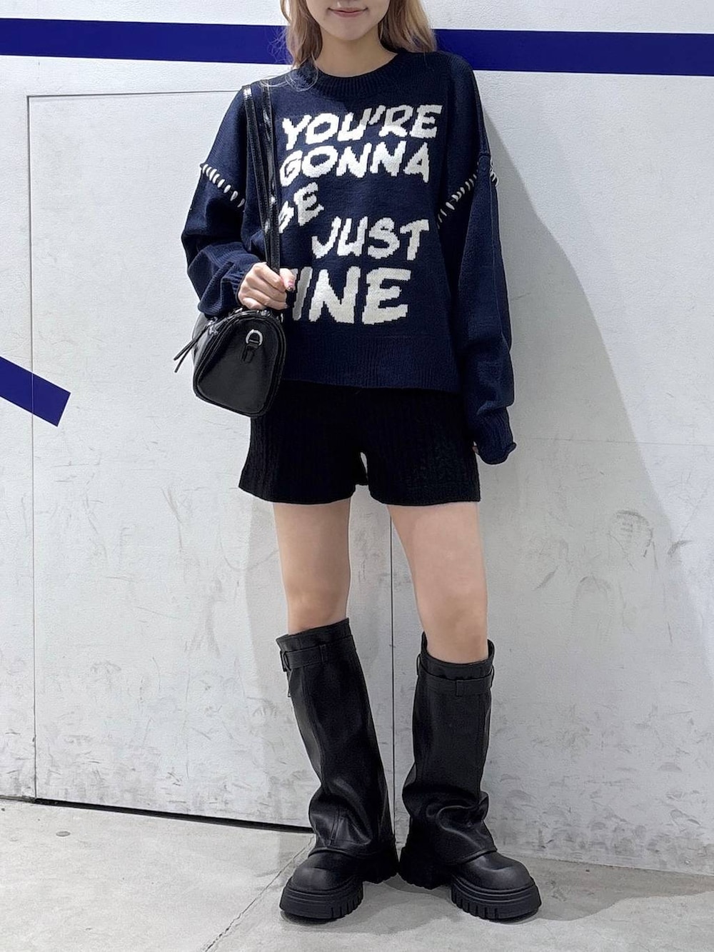 ブラック系のハンドバッグ、ブラック系のブーツ、ブルー系のニット/セーターを着用したレディースの秋コーディネートの2枚目の写真