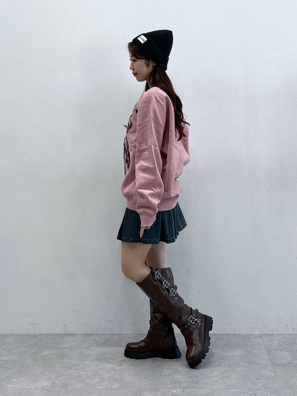 ブラック系のショルダーバッグ、ブルー系のデニムスカート、ブラウン系のブーツを着用したレディースの秋コーディネートの4枚目の写真