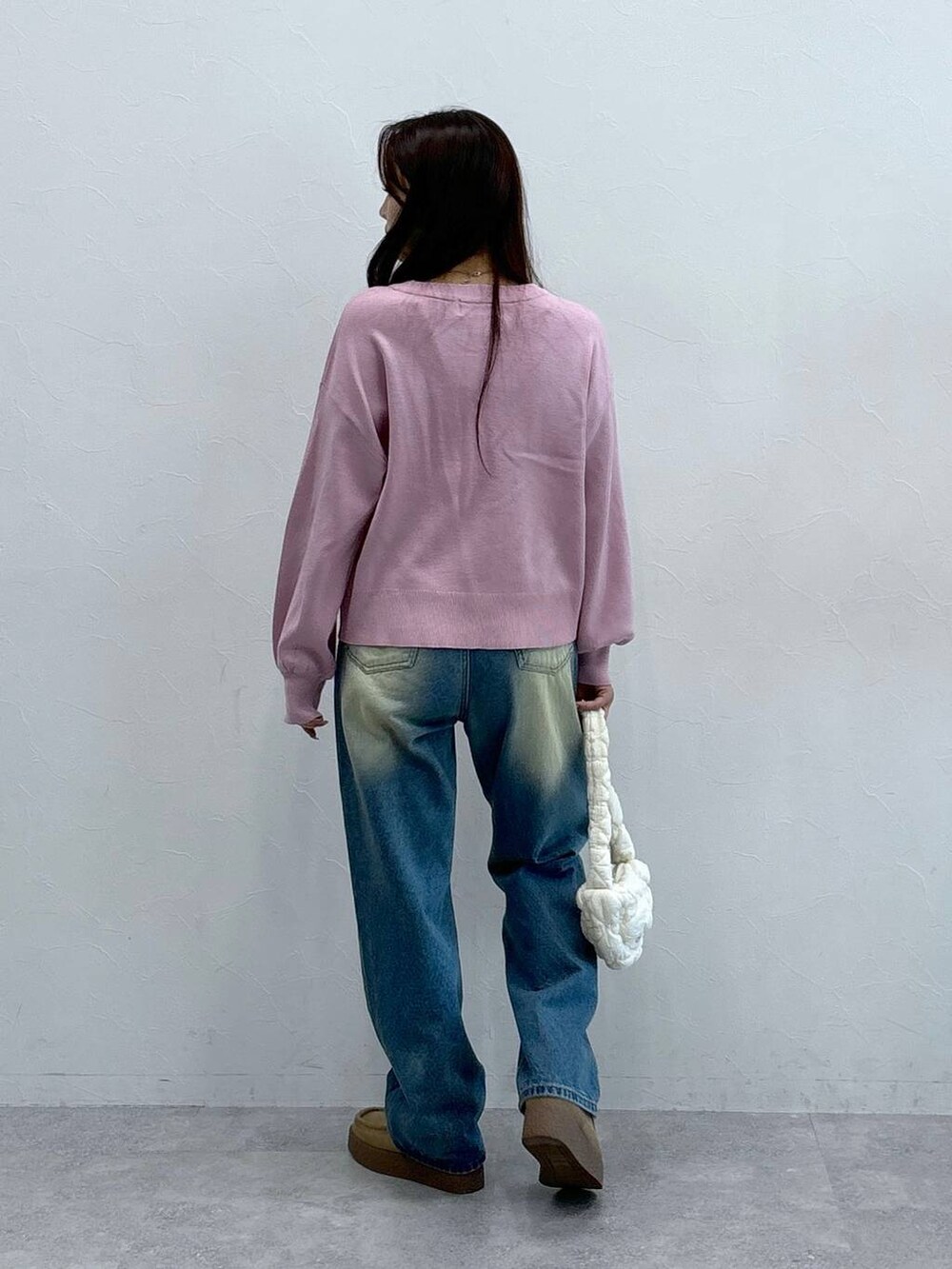 ホワイト系のショルダーバッグ、ピンク系のニット/セーター、ブルー系のデニムパンツを着用したレディースの秋コーディネートの4枚目の写真