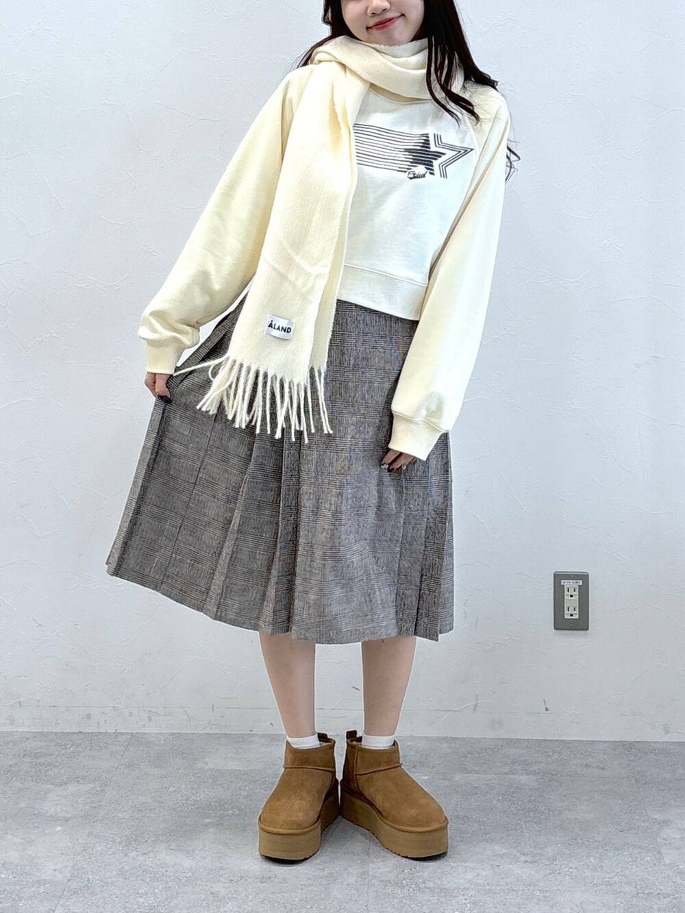 ブラウン系のスカート、ベージュ系のスウェット、ホワイト系のマフラーを着用したレディースの秋コーディネートの2枚目の写真