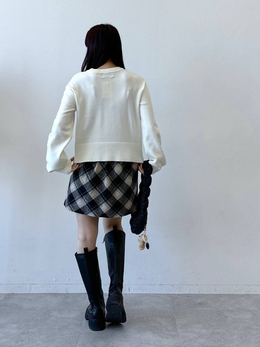 ブラック系のショルダーバッグ、ブラック系のスカート、ブラック系のブーツを着用したレディースの冬コーディネートの4枚目の写真