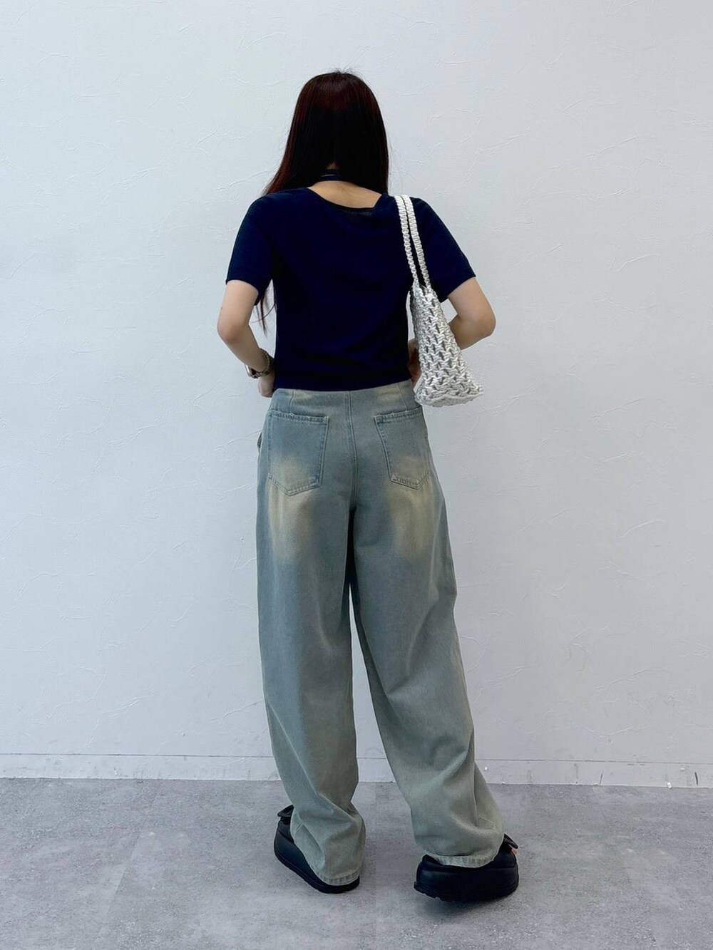 ブルー系のデニムパンツ、ブラック系のサンダル、ベージュ系のトートバッグを着用したレディースの夏コーディネートの5枚目の写真