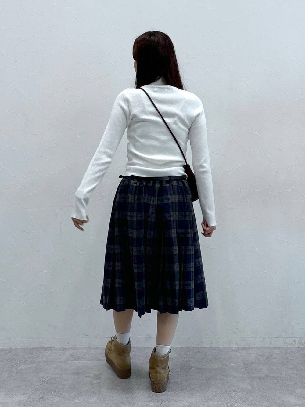 グレー系のスカート、ホワイト系のニット/セーター、ベージュ系のキーホルダーを着用したレディースの秋コーディネートの4枚目の写真