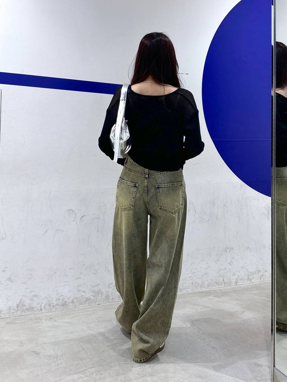 グレー系のトートバッグ、ブルー系のデニムパンツ、ベージュ系のチューブトップを着用したレディースの秋コーディネートの4枚目の写真