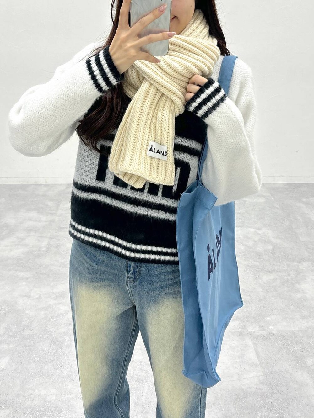 ブルー系のトートバッグ、ブルー系のデニムパンツ、ホワイト系のニット/セーターを着用したレディースの秋コーディネートの6枚目の写真