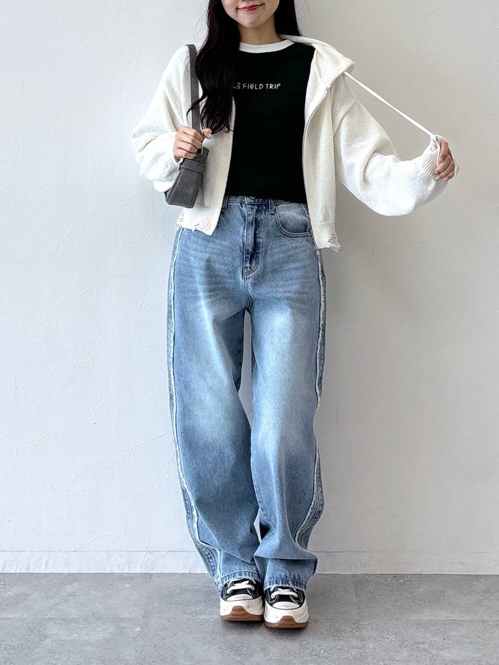 ブラック系のトートバッグ、ブラック系のTシャツ/カットソー、ブルー系のデニムパンツを着用したレディースの秋コーディネートの4枚目の写真