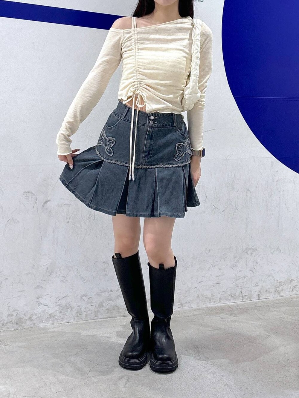 ホワイト系のショルダーバッグ、ベージュ系のTシャツ/カットソー、ブルー系のデニムスカートを着用したレディースの秋コーディネートの2枚目の写真