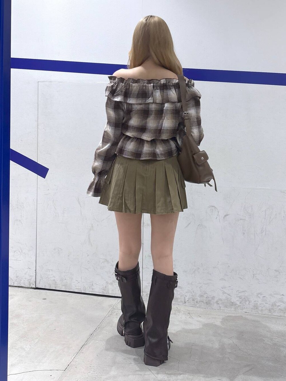 ブラウン系のショルダーバッグ、ベージュ系のスカート、ブラウン系のブーツを着用したレディースの秋コーディネートの5枚目の写真