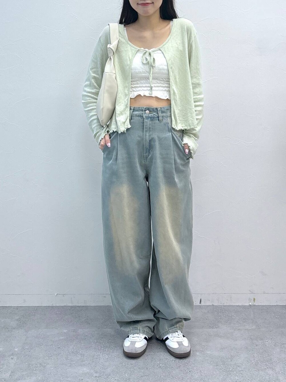 ブルー系のデニムパンツ、ベージュ系のチューブトップ、グリーン系のカーディガン/ボレロを着用したレディースの春コーディネートの3枚目の写真
