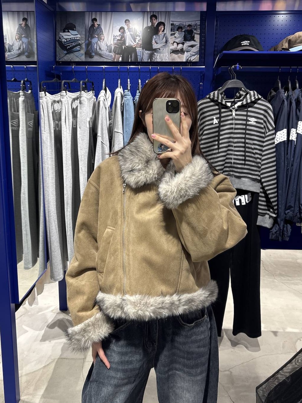 レッド系のTシャツ/カットソー、ブルー系のデニムパンツ、グレー系のムートンコートを着用したレディースの秋コーディネートの6枚目の写真