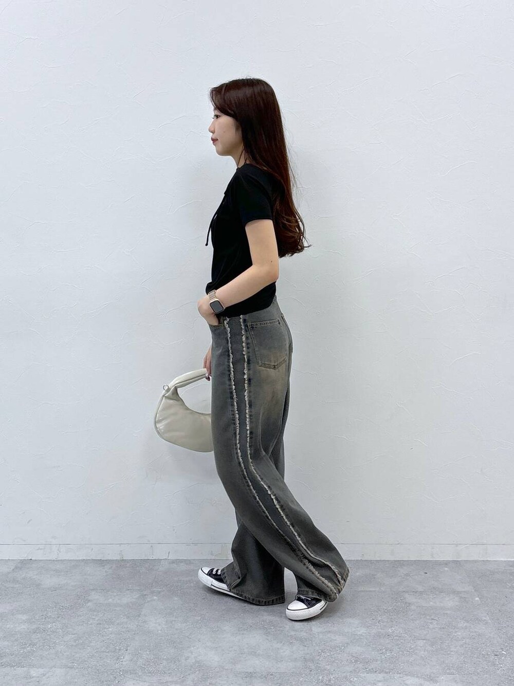 ブルー系のデニムパンツ、ホワイト系のハンドバッグ、ブラック系のTシャツ/カットソーを着用したレディースの夏コーディネートの3枚目の写真