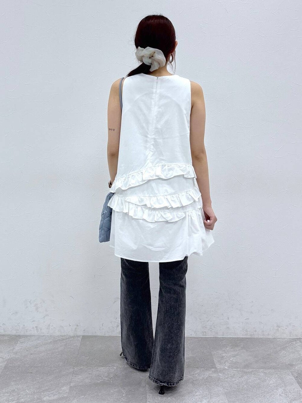 ブラック系のサンダル、ホワイト系のワンピース、ブラック系のデニムパンツを着用したレディースの夏コーディネートの4枚目の写真