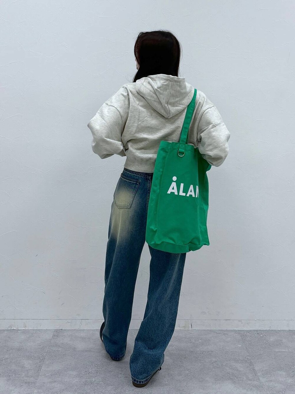 ブルー系のデニムパンツ、グリーン系のトートバッグを着用したレディースの秋コーディネートの4枚目の写真