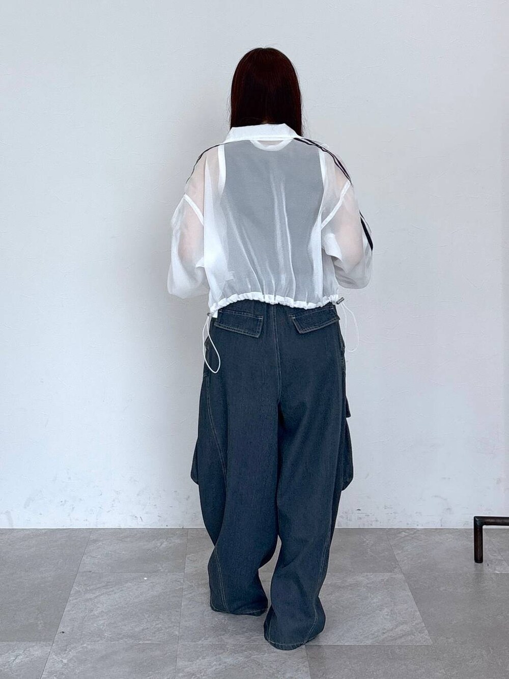 ブルー系のカーゴパンツ、ブラック系のタンクトップ、ホワイト系のブルゾンを着用したレディースの春コーディネートの6枚目の写真