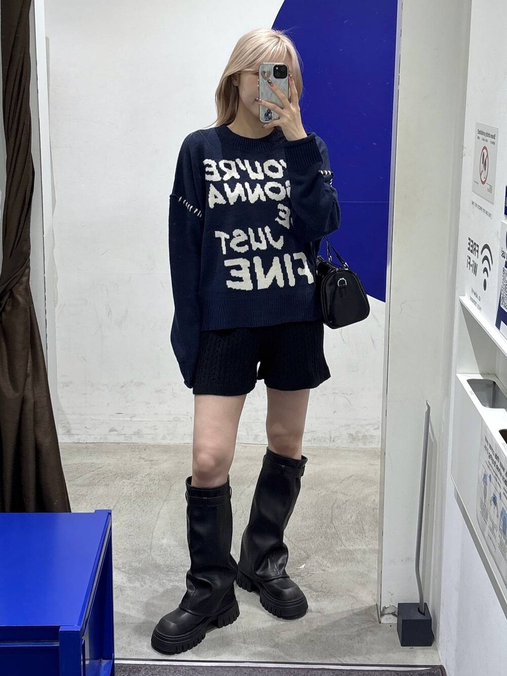 ブラック系のハンドバッグ、ブラック系のブーツ、ブルー系のニット/セーターを着用したレディースの秋コーディネートの5枚目の写真