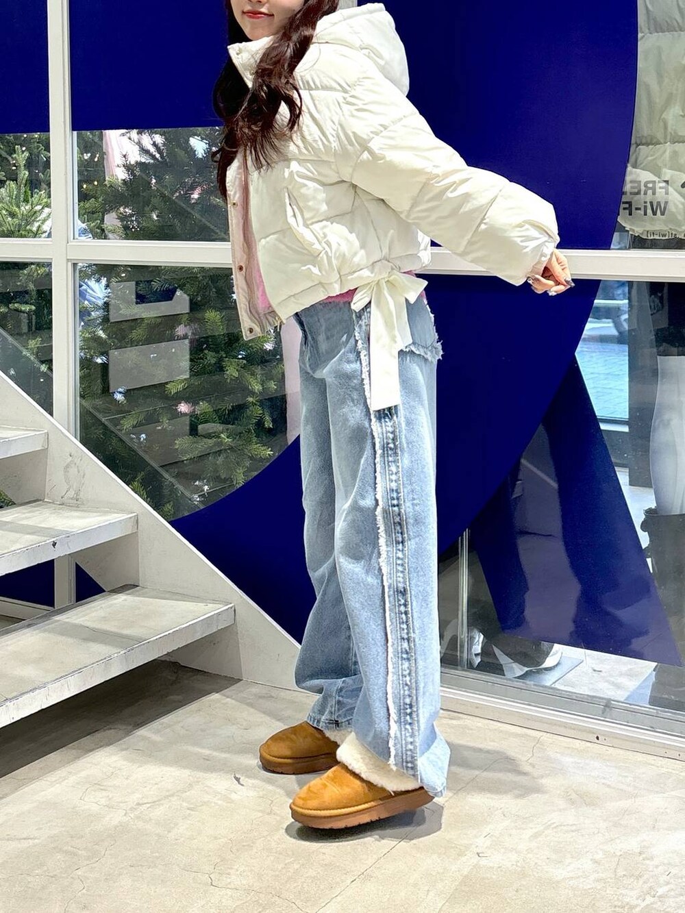 ホワイト系のダウンジャケット/コート、ピンク系のニット/セーター、ブルー系のデニムパンツを着用したレディースの秋コーディネートの5枚目の写真