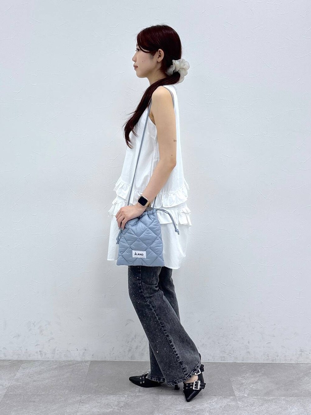 ブラック系のサンダル、ホワイト系のワンピース、ブラック系のデニムパンツを着用したレディースの夏コーディネートの3枚目の写真