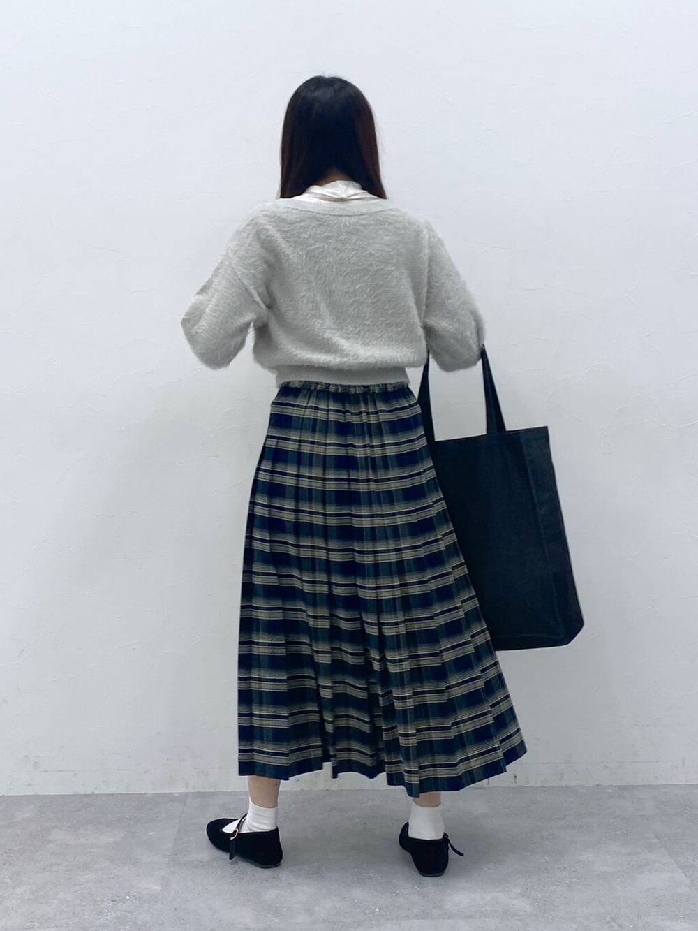 ブラック系のパンプス、ベージュ系のTシャツ/カットソー、ブルー系のスカートを着用したレディースの冬コーディネートの4枚目の写真