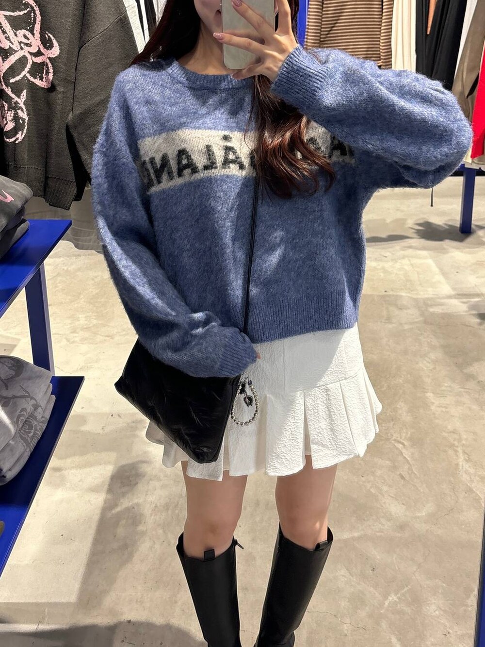 ホワイト系のスカート、ブラック系のブーツ、ブラック系のショルダーバッグを着用したレディースの秋コーディネートの6枚目の写真