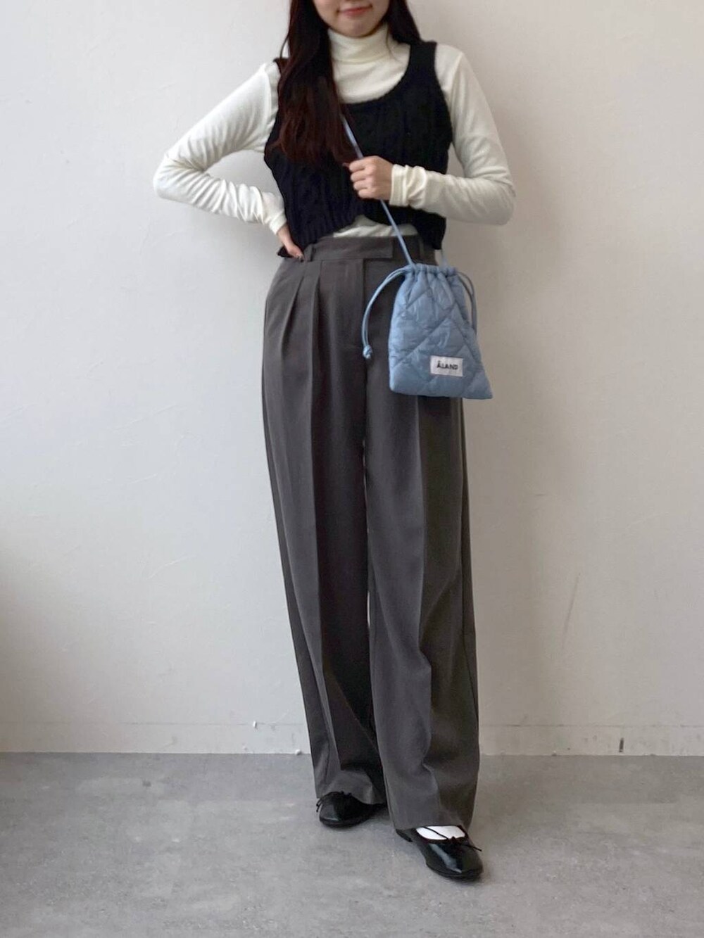 ブラック系のバレエシューズ、ブルー系のショルダーバッグ、グレー系のスラックスを着用したレディースの冬コーディネートの2枚目の写真