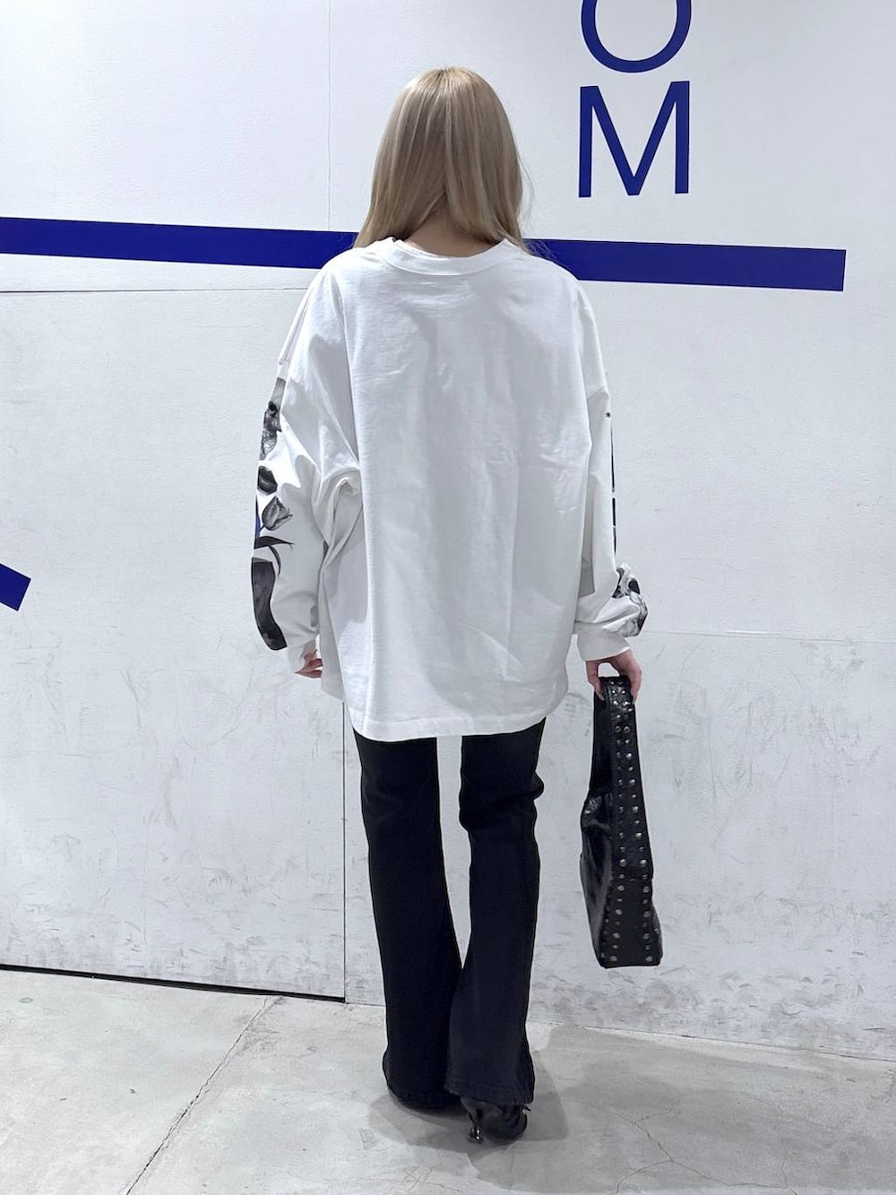 ブラック系のハンドバッグ、ブラック系のデニムパンツ、ブラック系のパンプスを着用したレディースの冬コーディネートの4枚目の写真