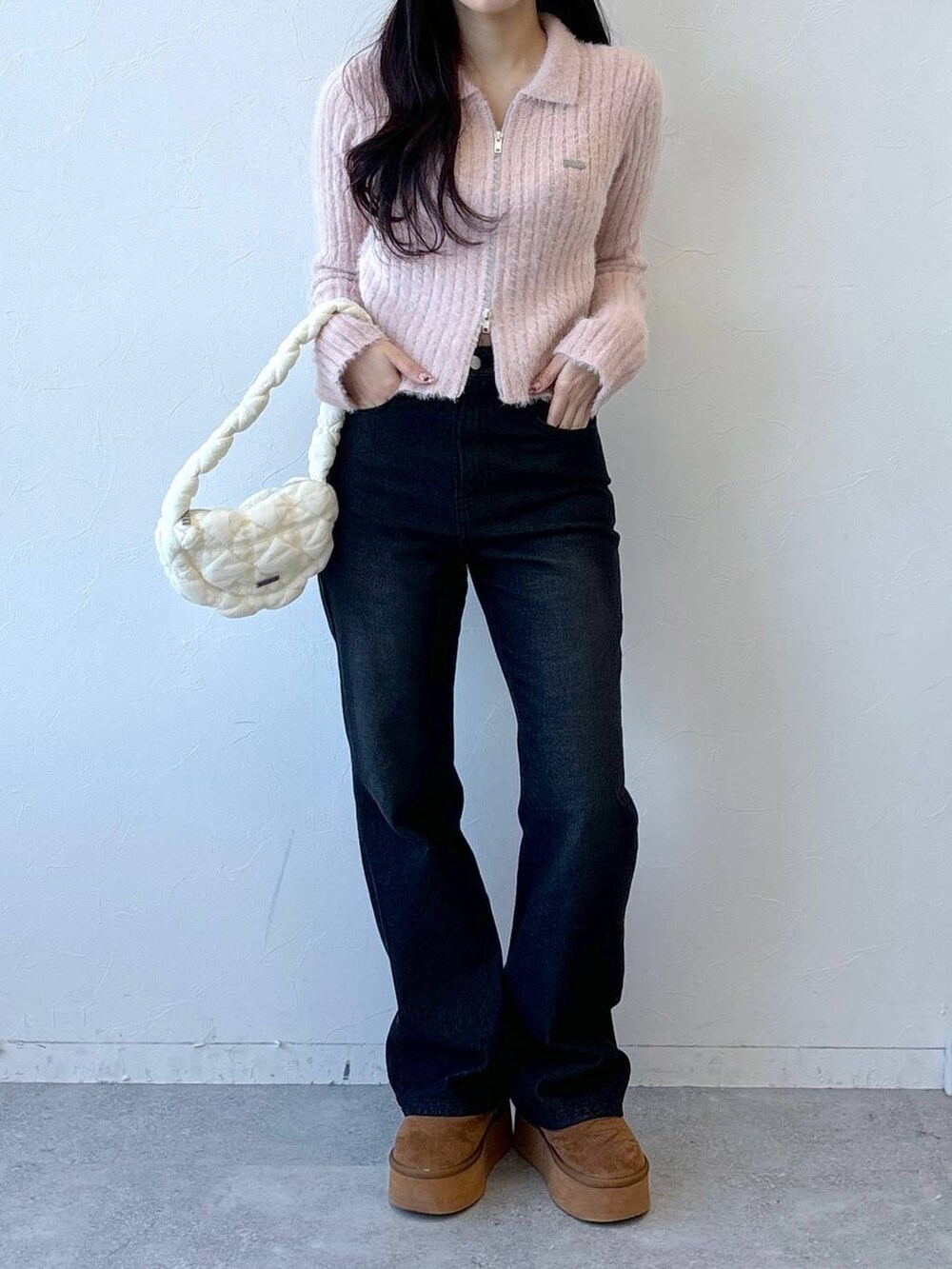 ホワイト系のショルダーバッグ、ブラック系のデニムパンツ、ピンク系のニット/セーターを着用したレディースの冬コーディネートの2枚目の写真