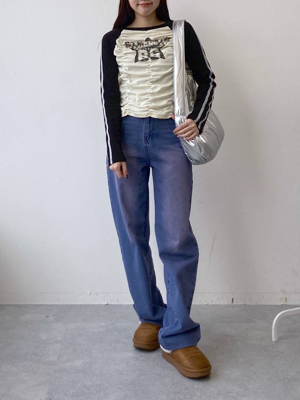 パープル系のデニムパンツ、その他のショルダーバッグ、ベージュ系のTシャツ/カットソーを着用したレディースの冬コーディネートの2枚目の写真