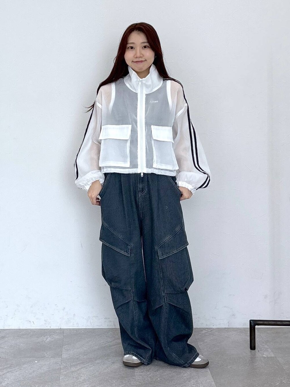 ブルー系のカーゴパンツ、ブラック系のタンクトップ、ホワイト系のブルゾンを着用したレディースの春コーディネートの2枚目の写真