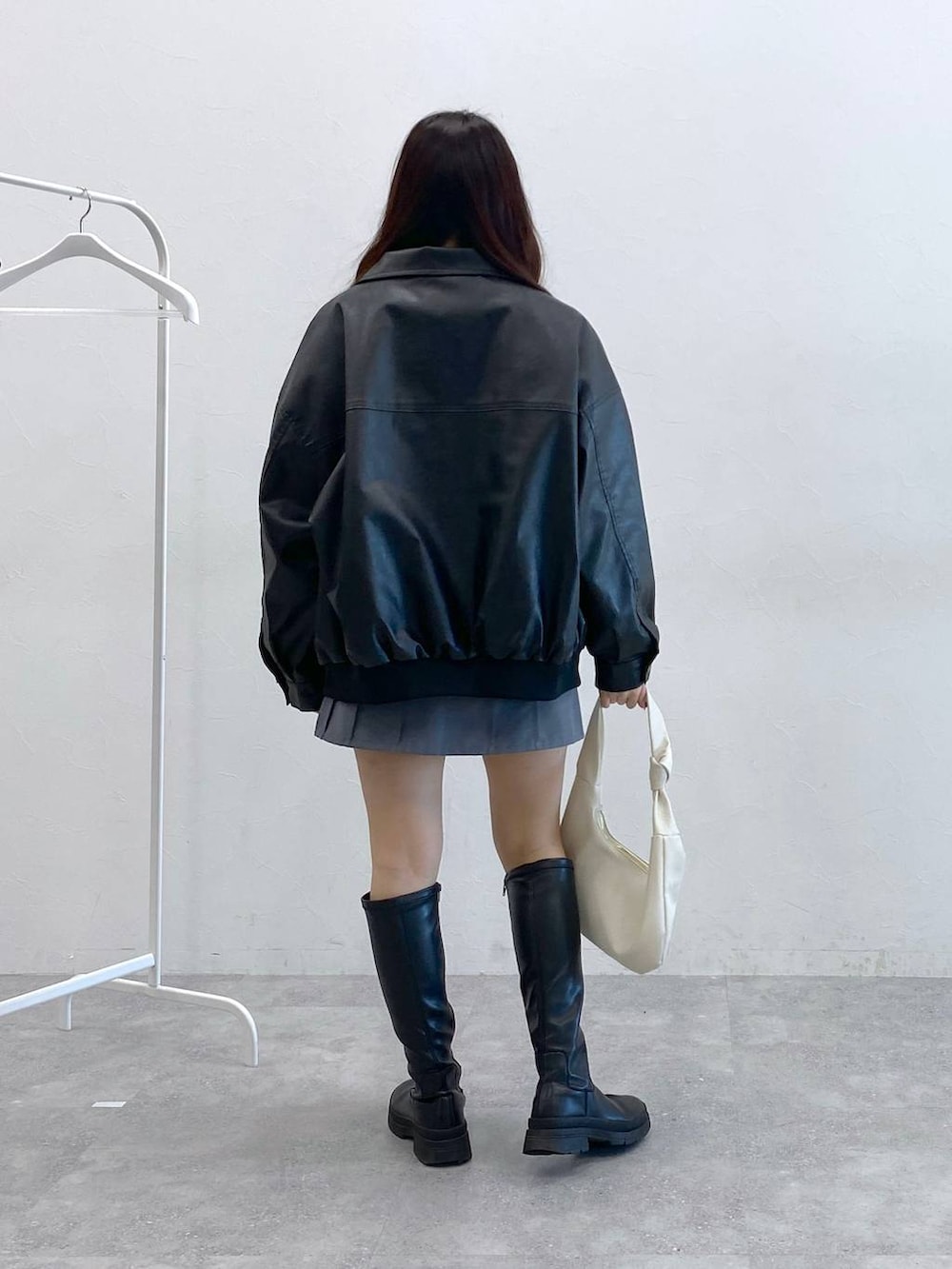 グレー系のスカート、ブラック系のブルゾン、ベージュ系のTシャツ/カットソーを着用したレディースの冬コーディネートの4枚目の写真