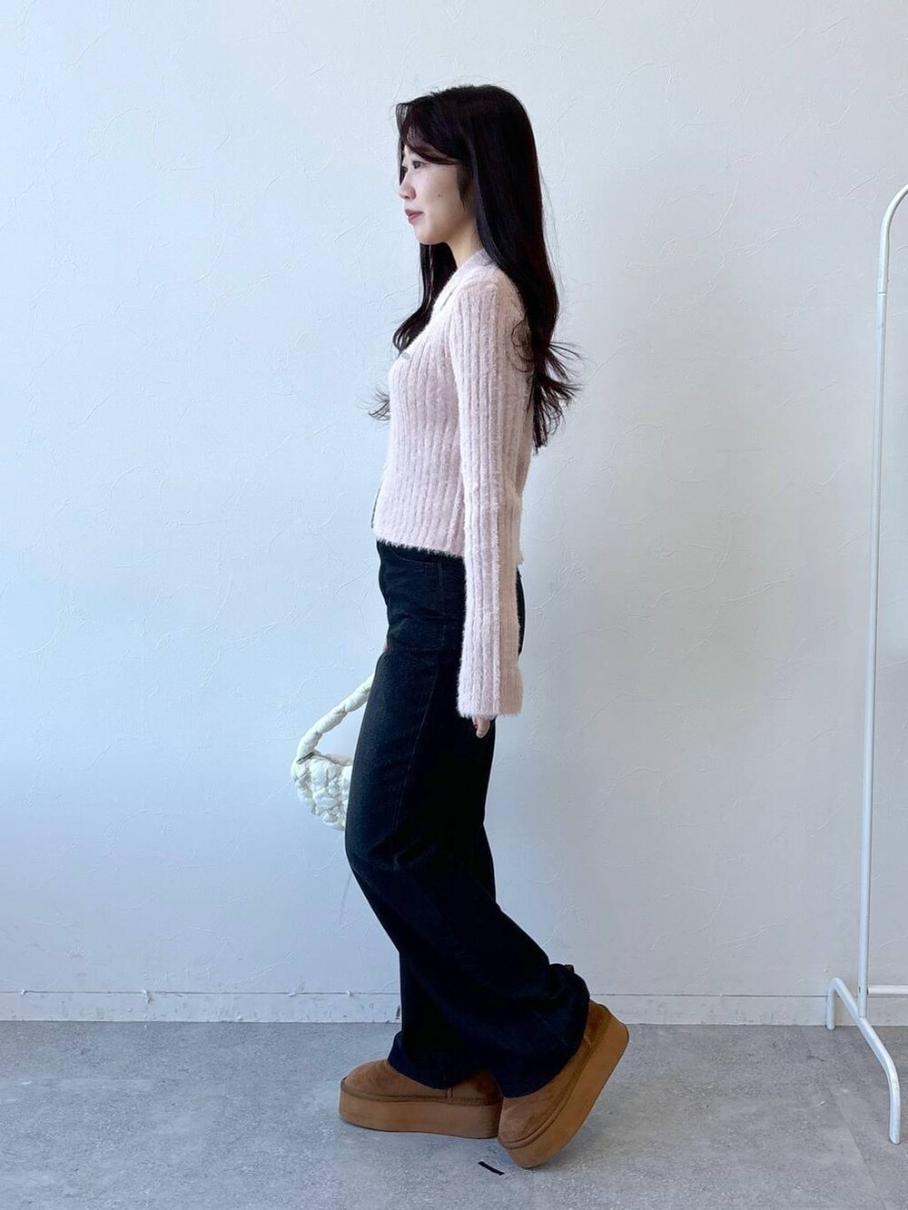 ホワイト系のショルダーバッグ、ブラック系のデニムパンツ、ピンク系のニット/セーターを着用したレディースの冬コーディネートの3枚目の写真