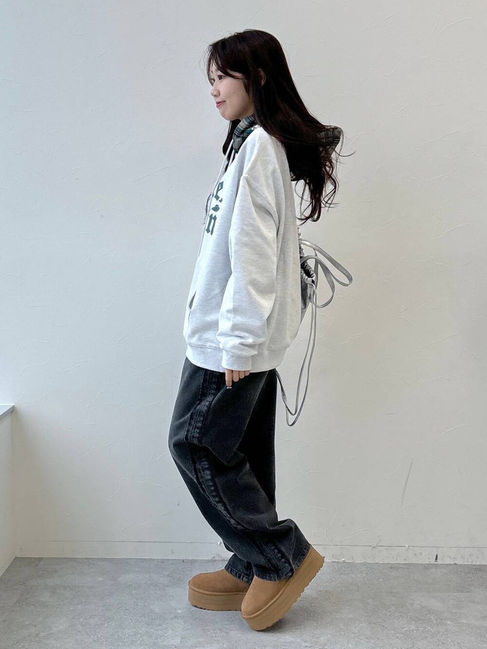 グレー系のデニムパンツ、グレー系のパーカー、グレー系のバックパック/リュックを着用したレディースの秋コーディネートの3枚目の写真