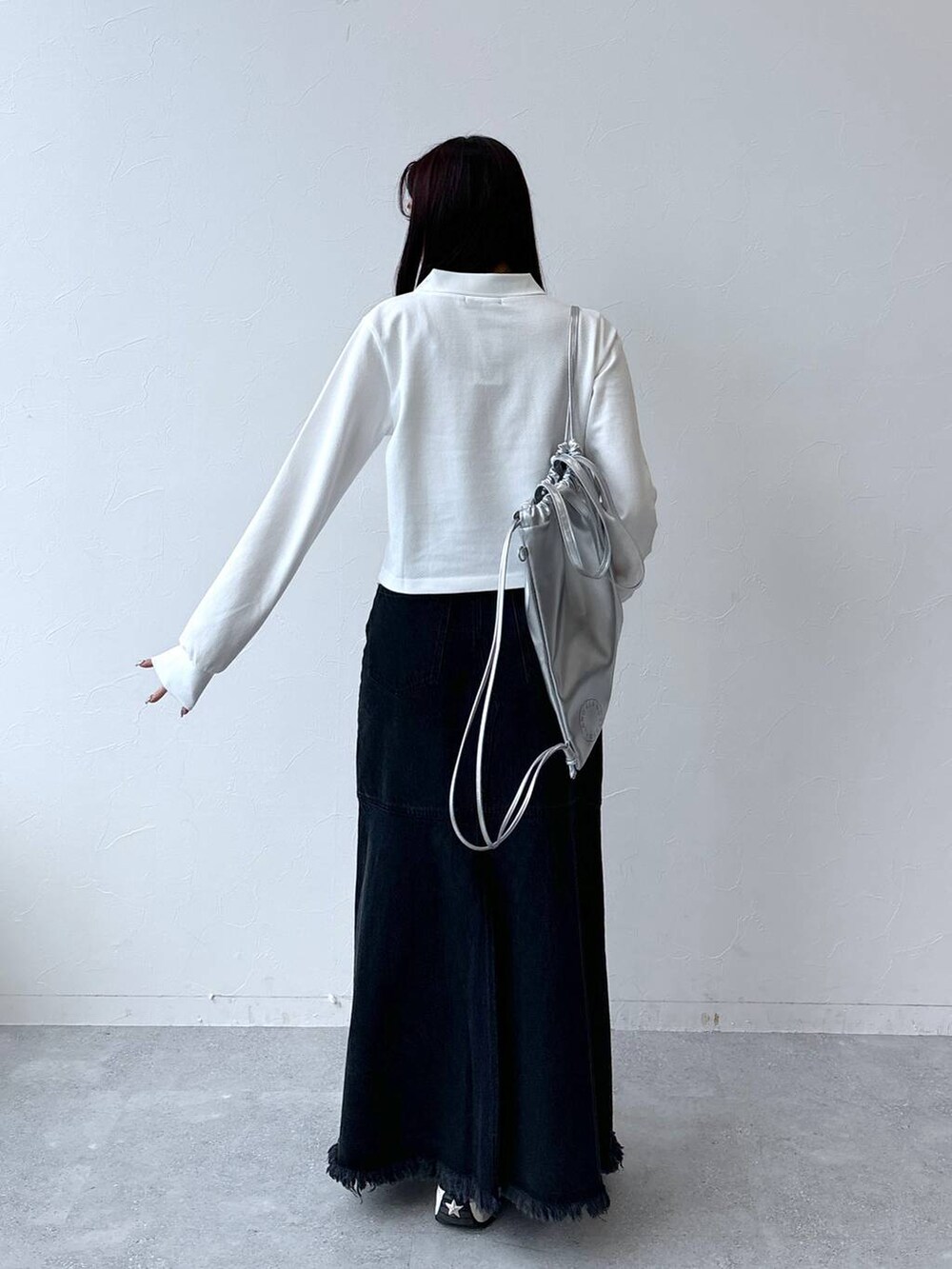 ブラック系のデニムスカート、グレー系のバックパック/リュック、ホワイト系のポロシャツを着用したレディースの秋コーディネートの4枚目の写真